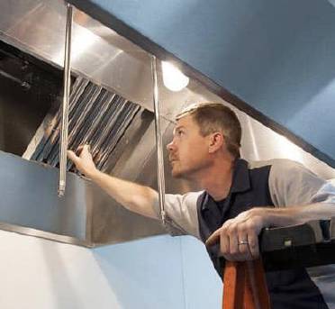 Maintenance professional opening exhaust hood with IKECA certification badge overlayed